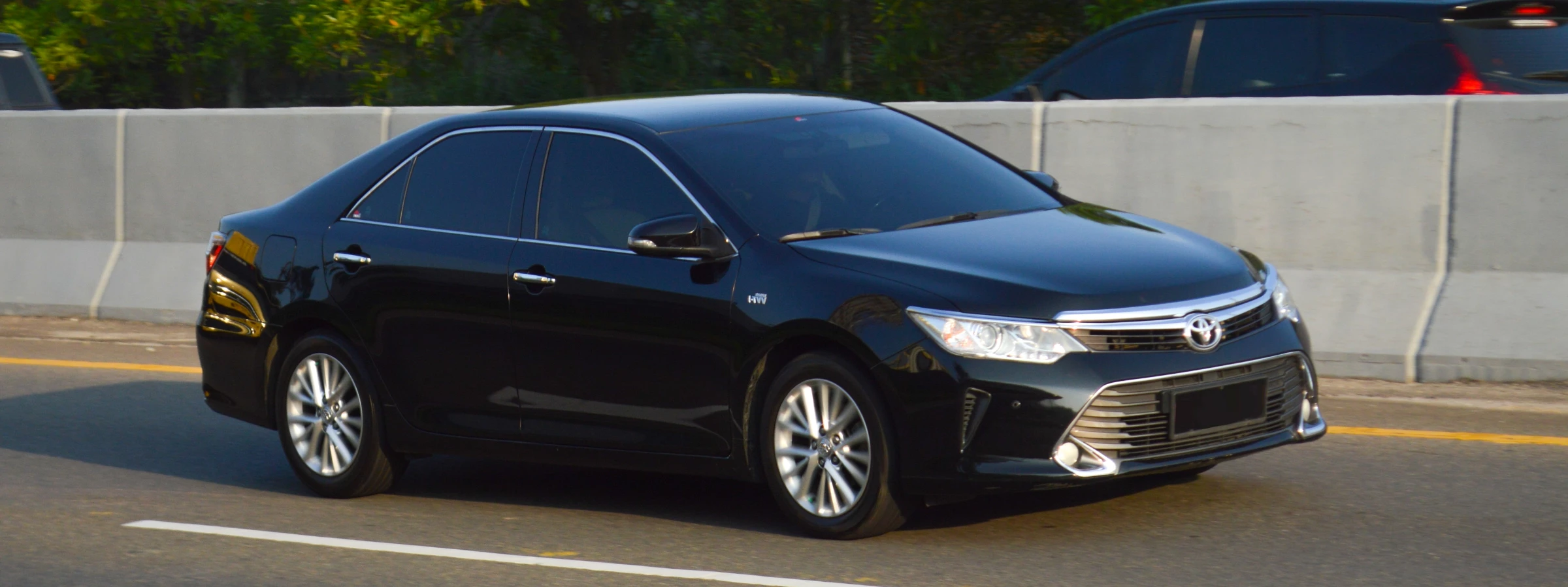 A black Toyota Camry cruising down a highway.