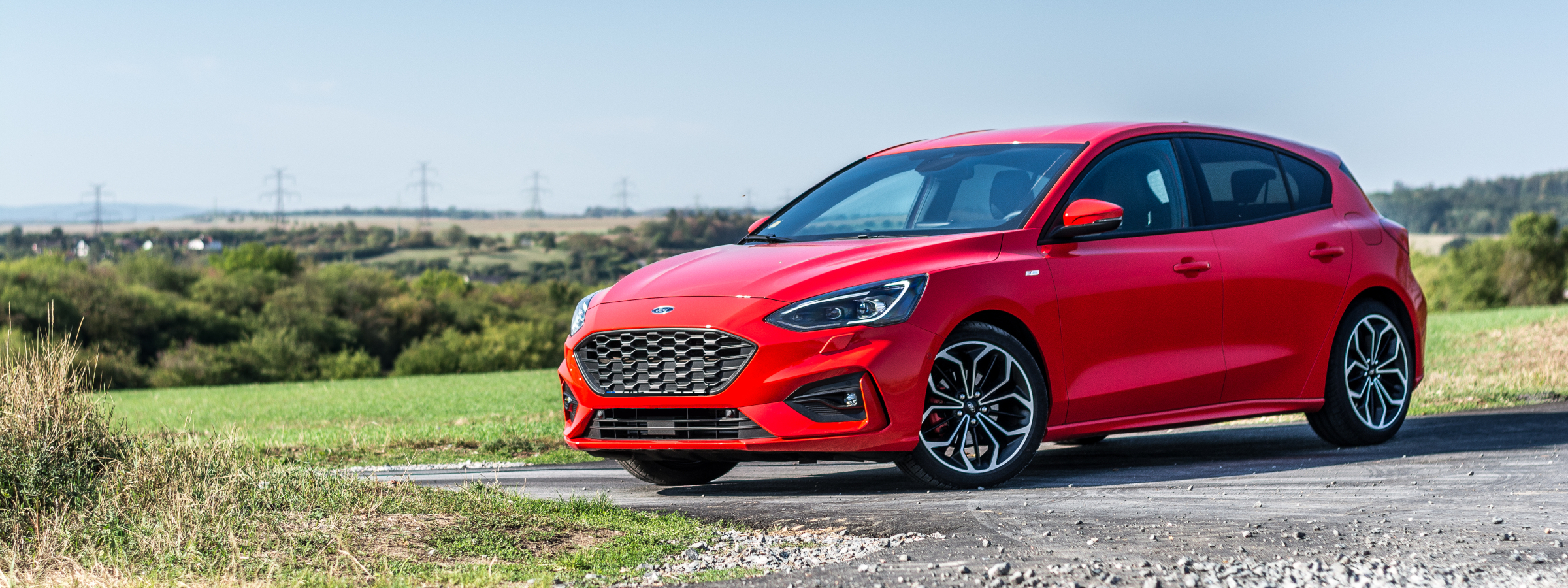 A red Ford Focus parked in front of a field