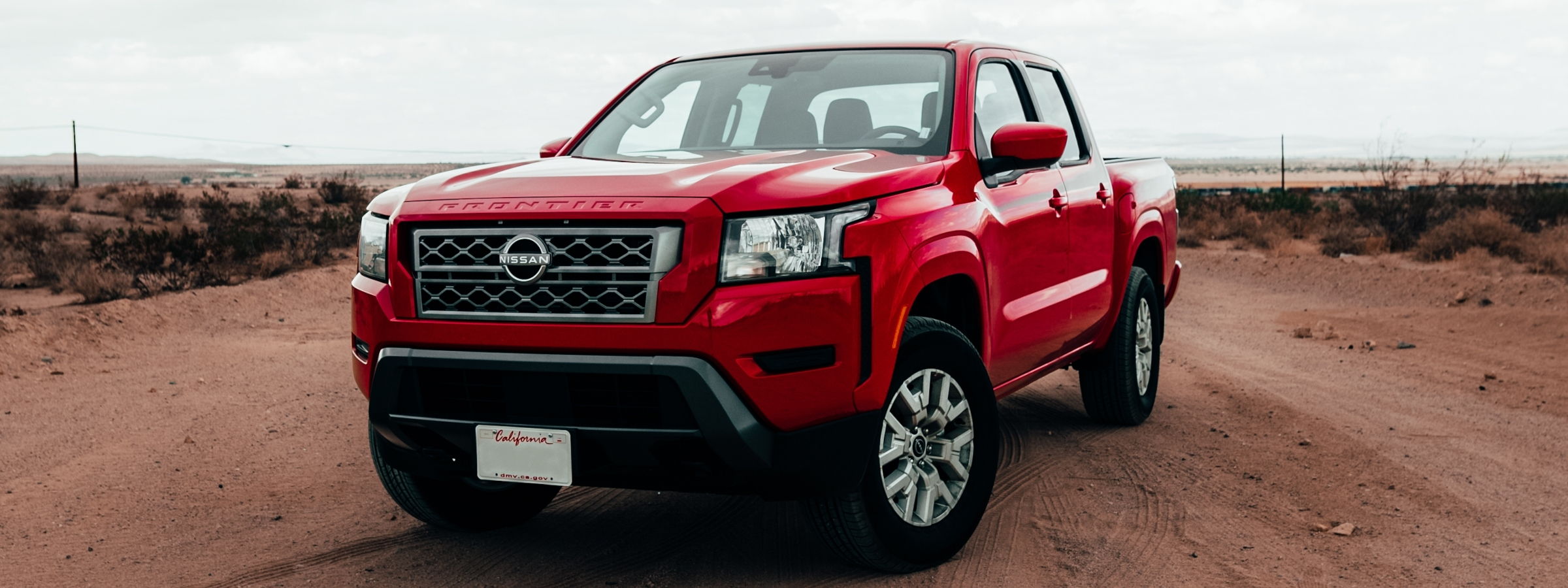 A dashing red nissan frontier parked on a desert road