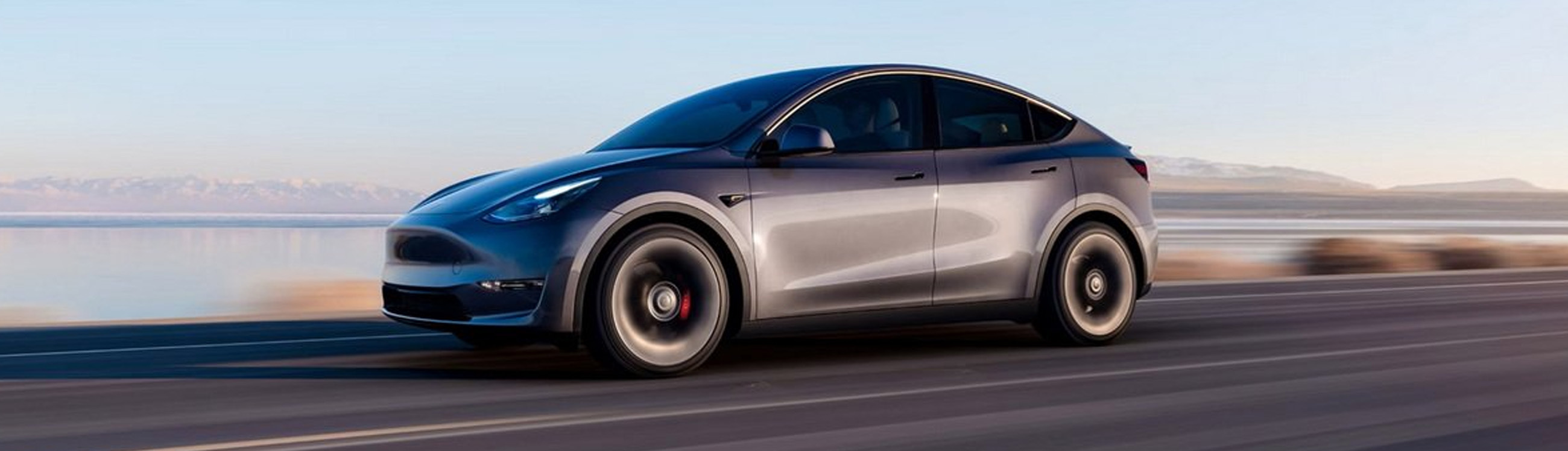 A gray Tesla Model Y driving through a scenic route