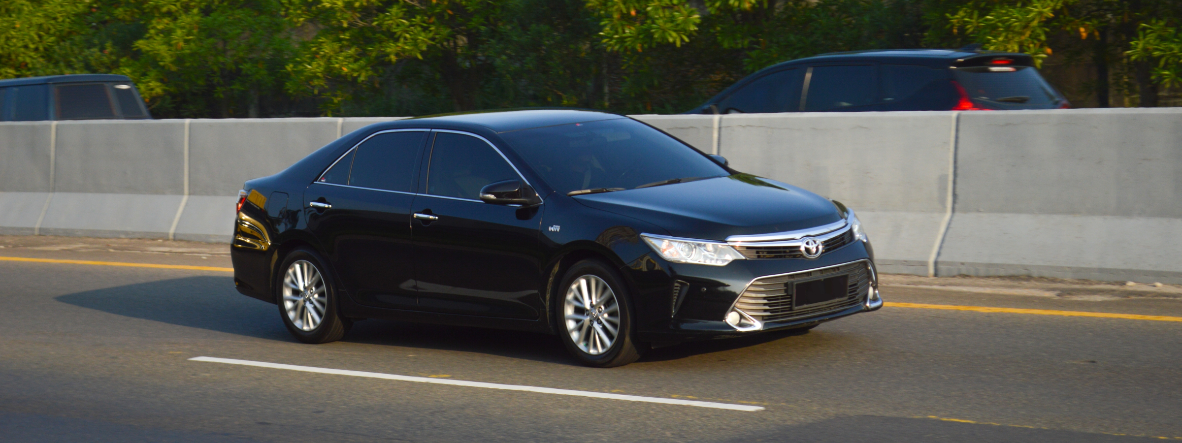 A black Toyota Camry driving down the highway