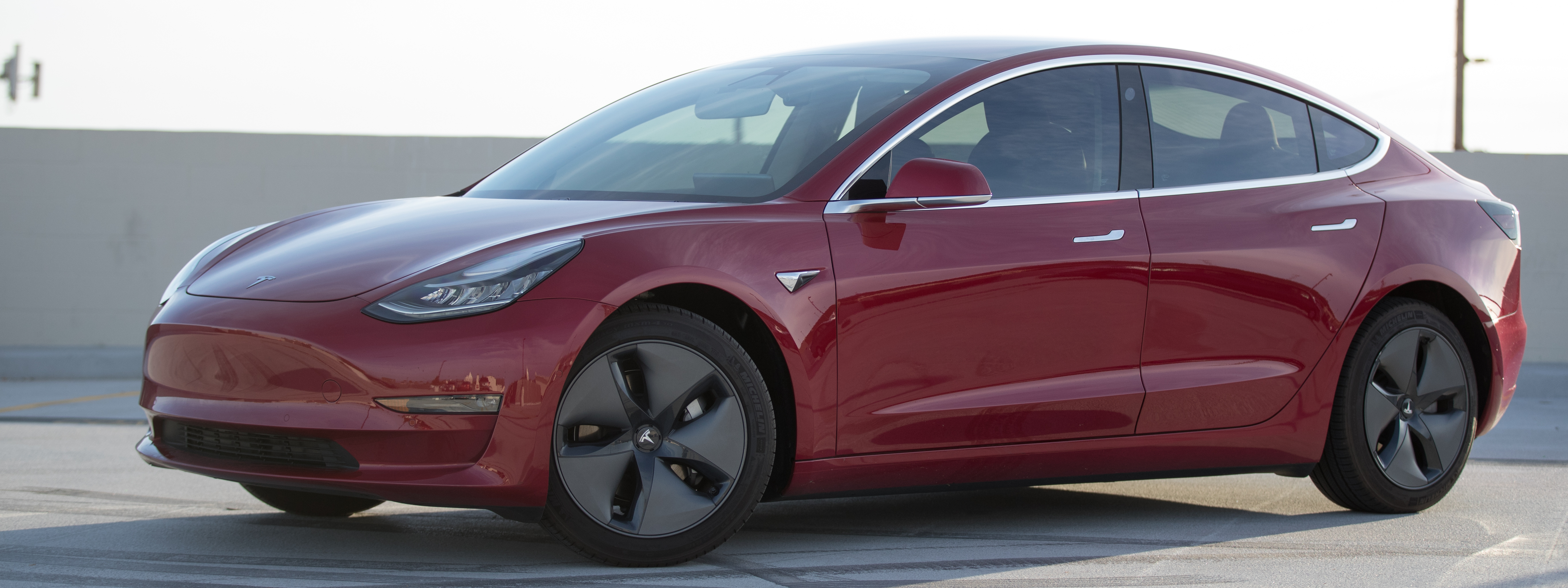 A red Tesla Model 3 in an LA parking lot.