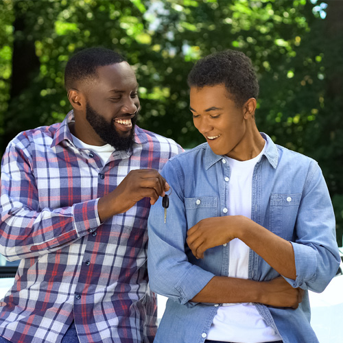 Man handing his son car keys.