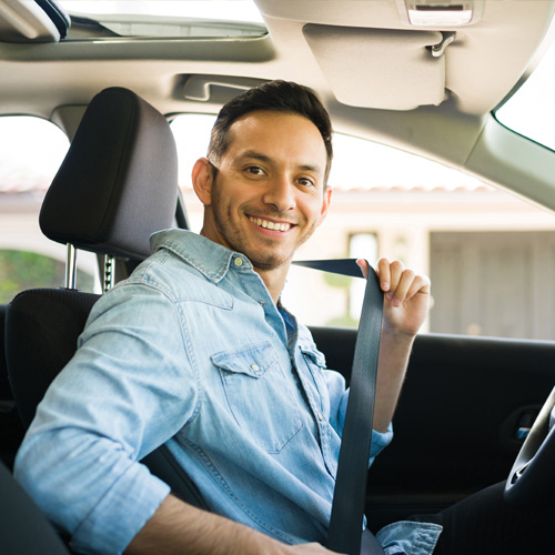 Smiling man putting on a seatbelt.