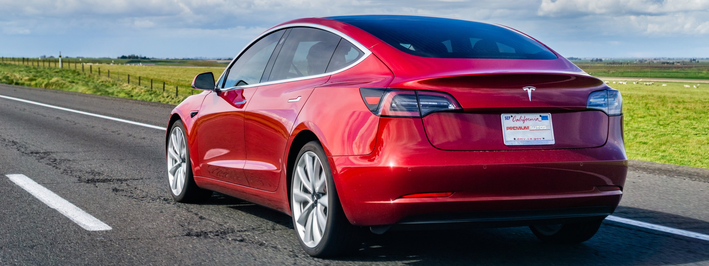 A red Tesla driving a scenic route