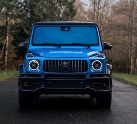 Blue Mercedes-Benz G-Class on a tree-lined road