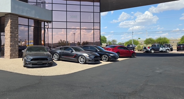 Used sports cars and sedans parked in front of the Paramount Auto Sales showroom in Tucson