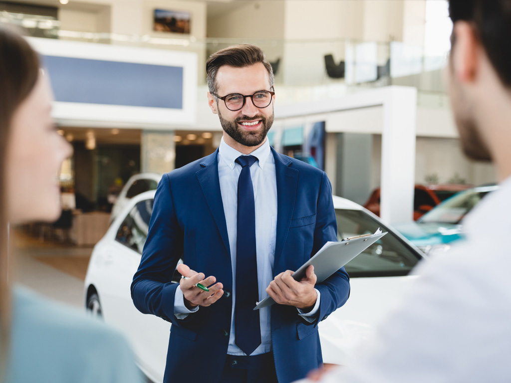 Couple at a dealership speaking with a helpful salesman.