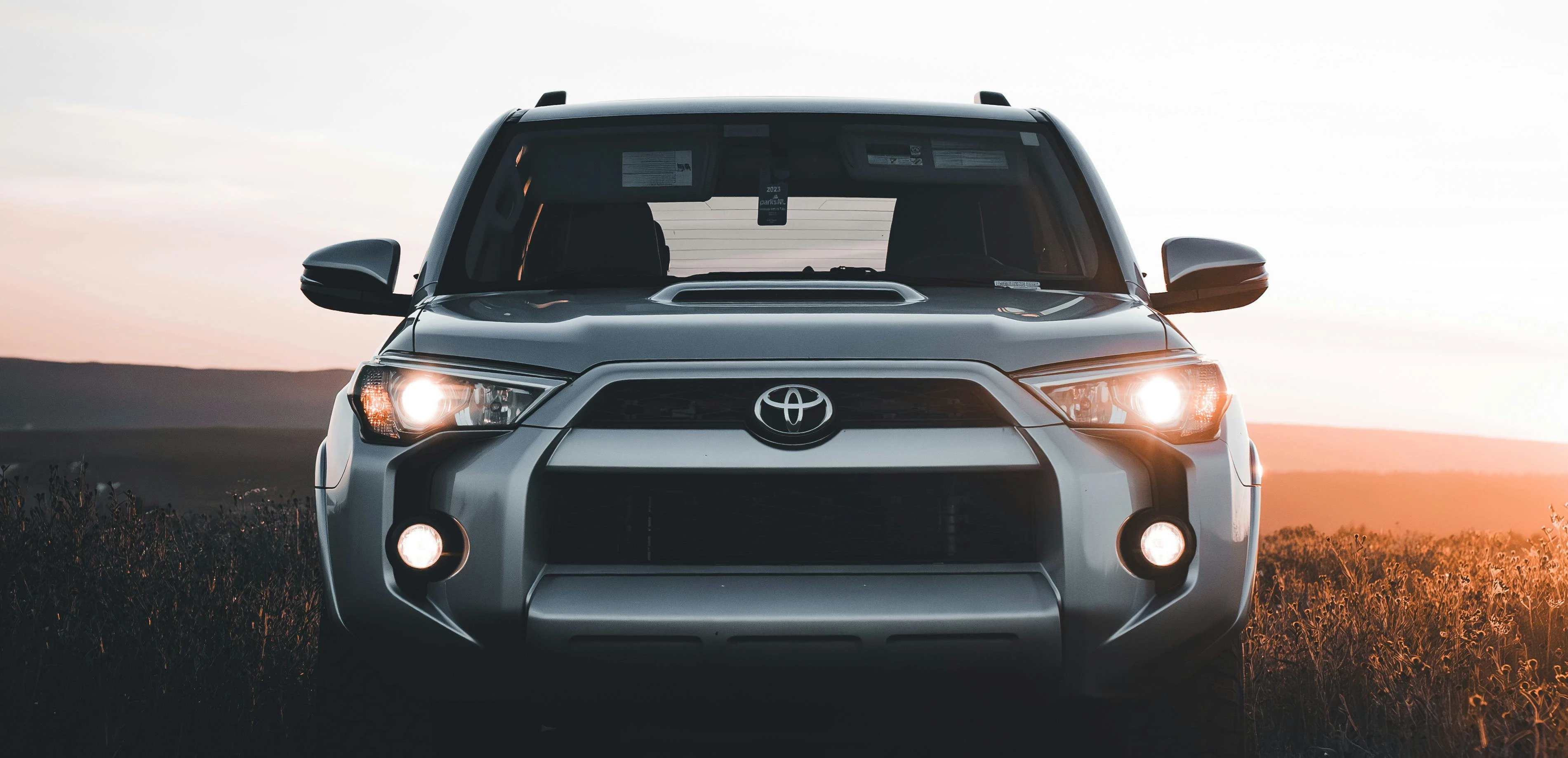 A Toyota SUV in a field at sunset.