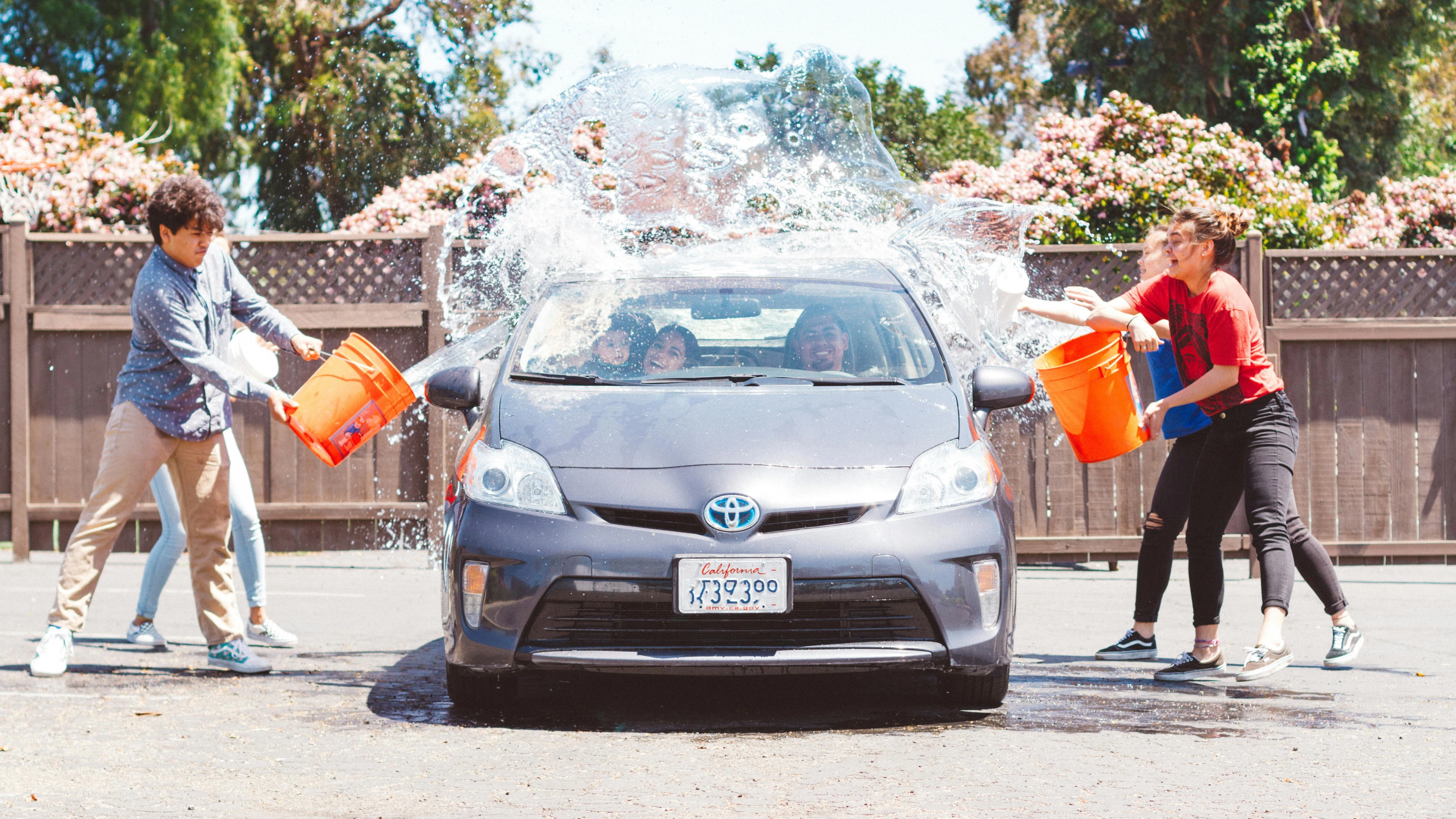 Young drivers working together to wash a Toyota.