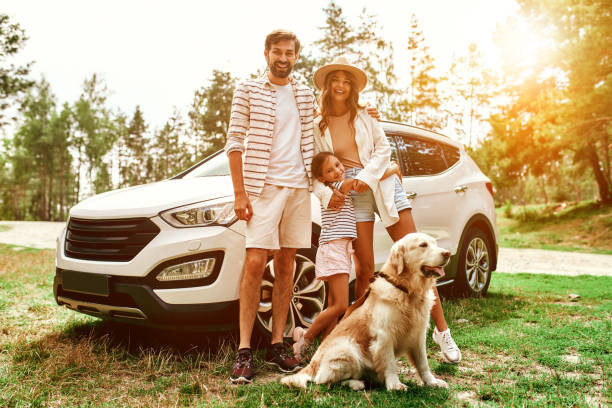 Happy family posing in nature with their vehicle after being approved for a car loan with bad credit with Byron center Motors in Byron Center MI