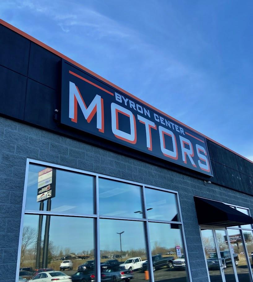 Front entrance with building sign for Byron Center Motors used car dealership in Byron Center MI