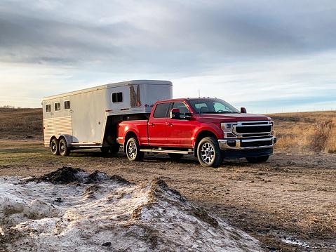 Red towing truck towing camper in wilderness. Towing trucks for sale in Byron Center MI