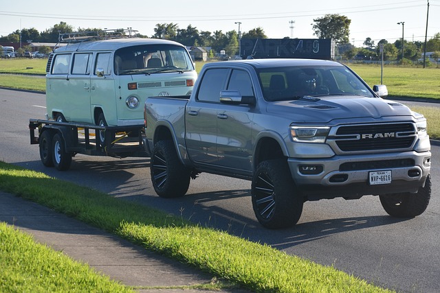 Large silver ram truck towing a trailer with a vehicle on it on a road, Byron Center MI