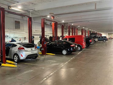 Indoor Service Bays with gray hatchback, black sedan, and red van